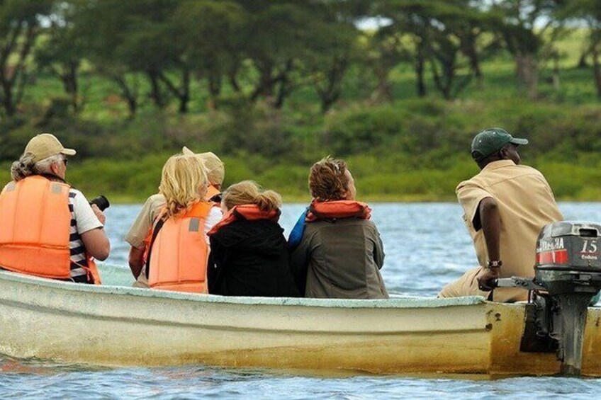 A group of people in a small boat on a body of water with trees in the background. 5