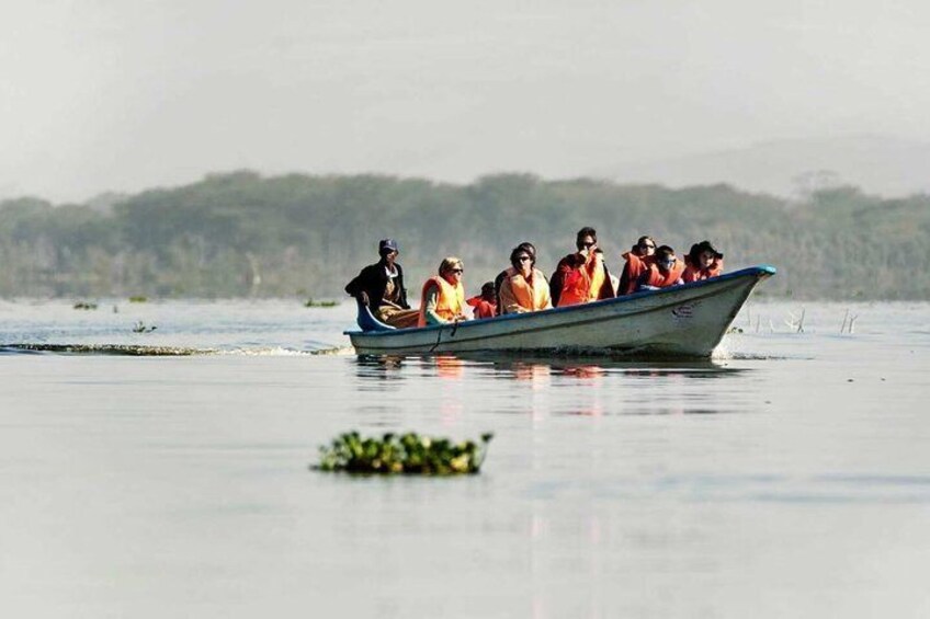 A group of people in a boat on calm water with a forested shoreline in the background. 2