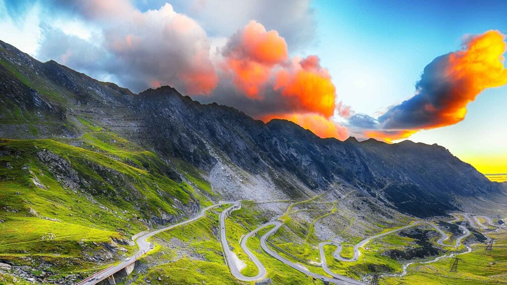 A winding mountain road with green grass and rocky terrain. 3