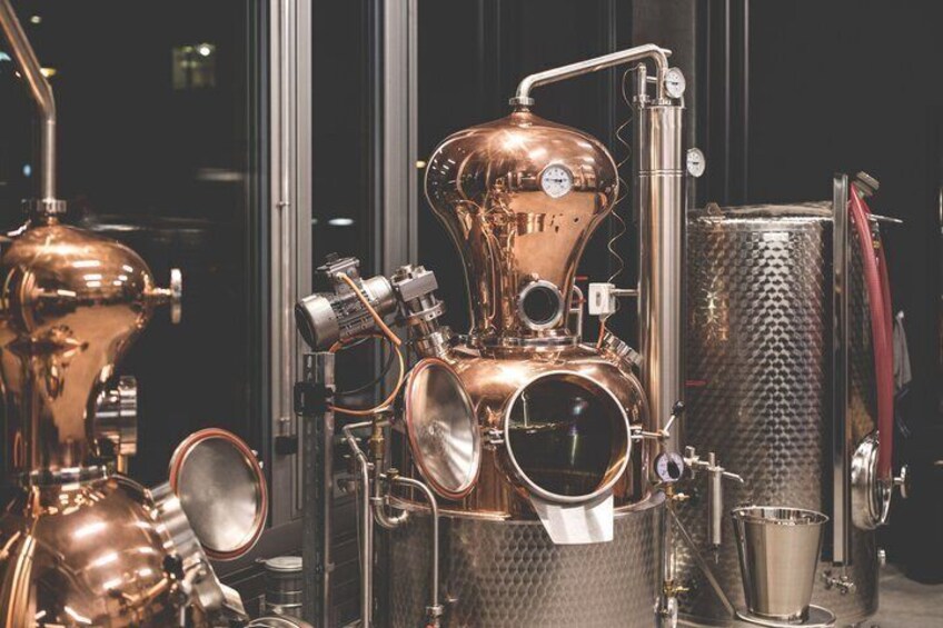 A copper distillation apparatus with gauges and a glass container. 4
