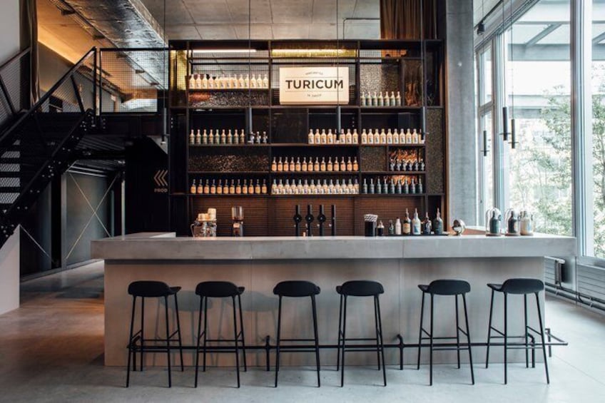A bar with a sign reading 'TURICUM' and a variety of bottles on shelves. 1