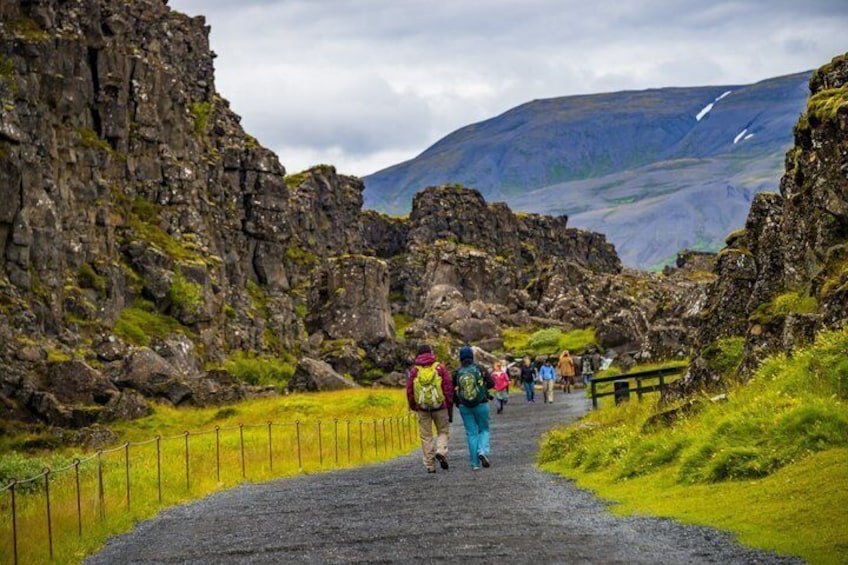 A rocky path with hikers, surrounded by rugged terrain and a cloudy sky. 5