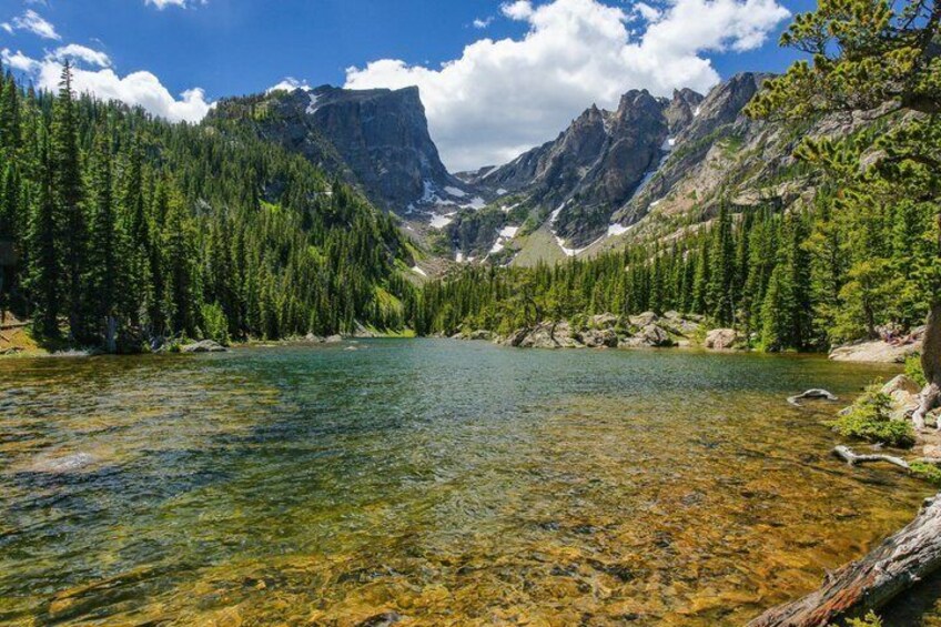 A clear mountain lake surrounded by dense forest and rocky mountains. 3