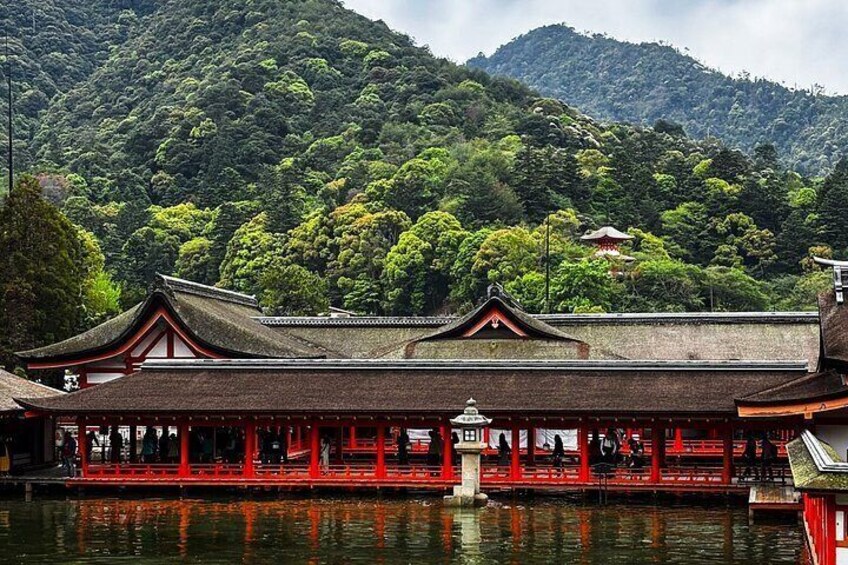 A traditional Japanese building with a red roof and wooden structure, surrounded by water and lush green mountains. 4