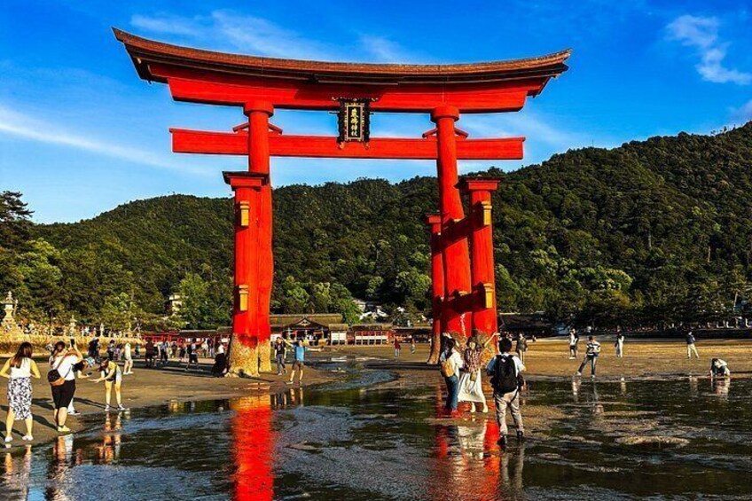 A red torii gate with people walking around it. 3