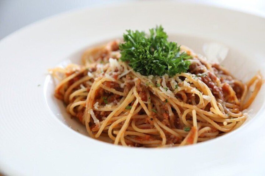 A plate of spaghetti with tomato sauce, topped with grated cheese and parsley. 5