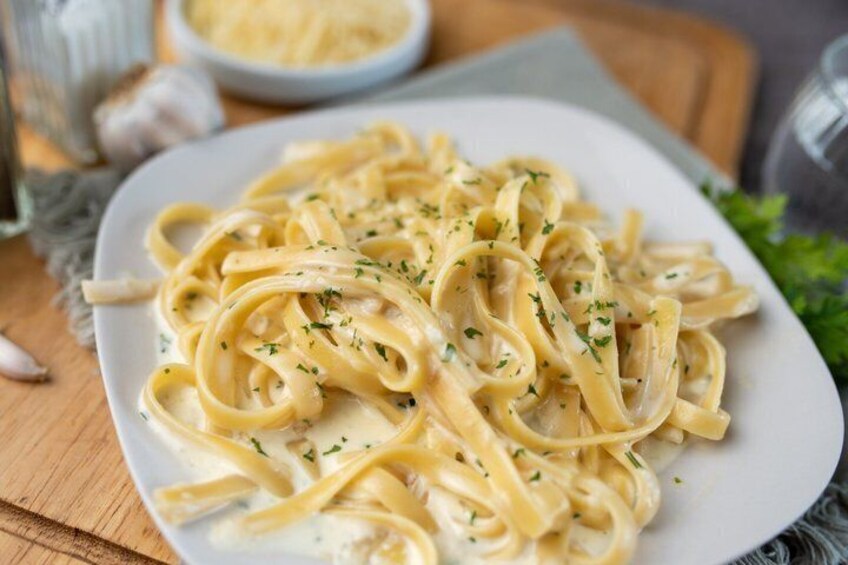 A plate of pasta with a creamy sauce and herbs. 2