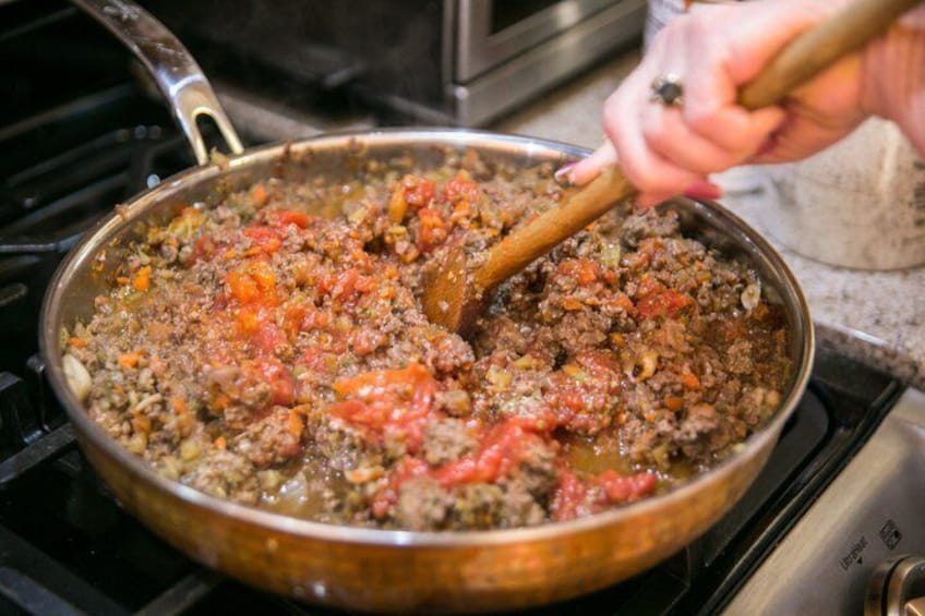 A person cooking a dish in a pan on a stove. 3