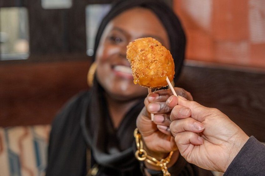 A person holding a fried food item on a stick. 4