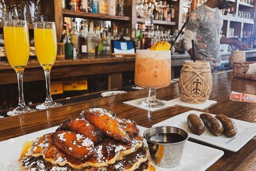 A bar with a dessert plate of pancakes, a drink with a straw, and a decorative jar. 2