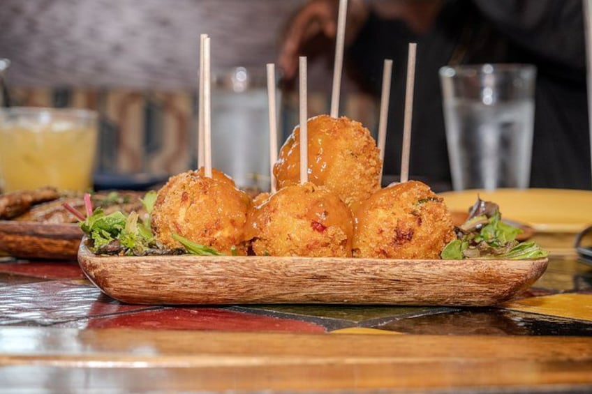 A wooden bowl with fried food items, possibly chicken, on a table. 3