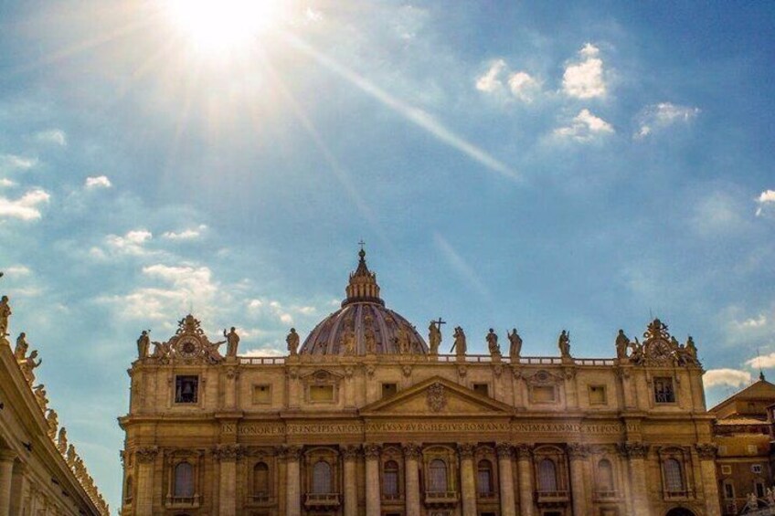 A grand building with a large dome and statues, under a clear sky with the sun shining. 3