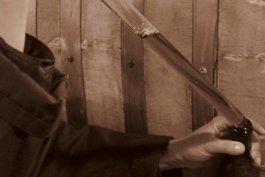 A person holding a long, thin object, possibly a tool, against a wooden background. 3