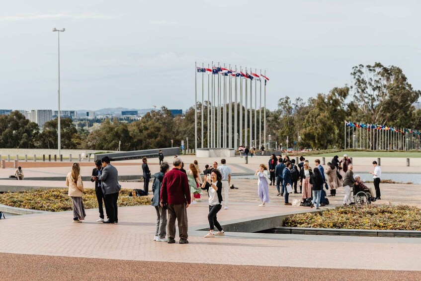 A public square with people walking, a flag monument, and a cityscape in the background. 5