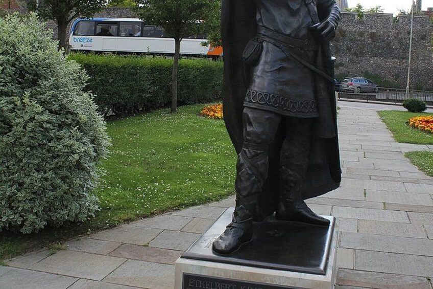 A statue of a person in a long coat and boots on a pedestal. 4