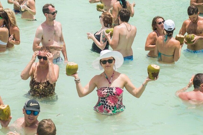 People in a swimming pool holding coconuts. 3