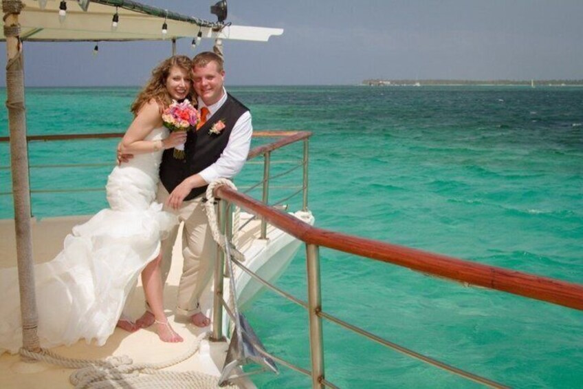 A couple on a boat with turquoise water and a clear sky. 4