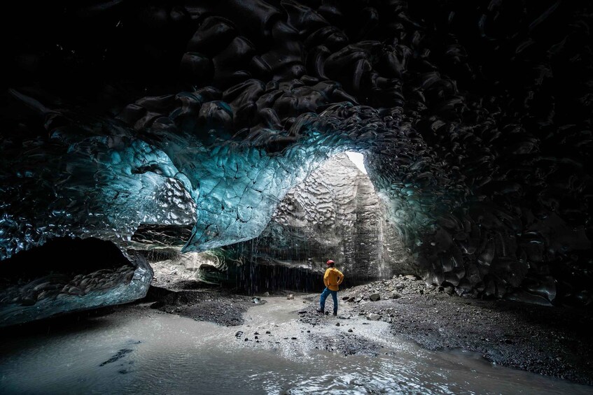 Eine Person steht in einer Höhle mit einem Wasserfall. 2