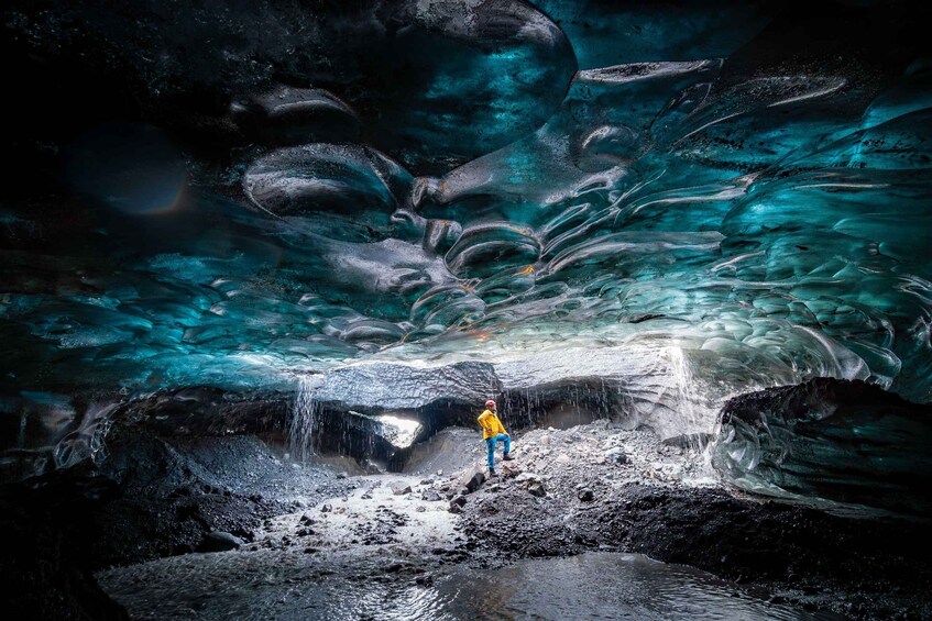 Eine Person steht in einer Höhle mit einem Wasserfall. 1