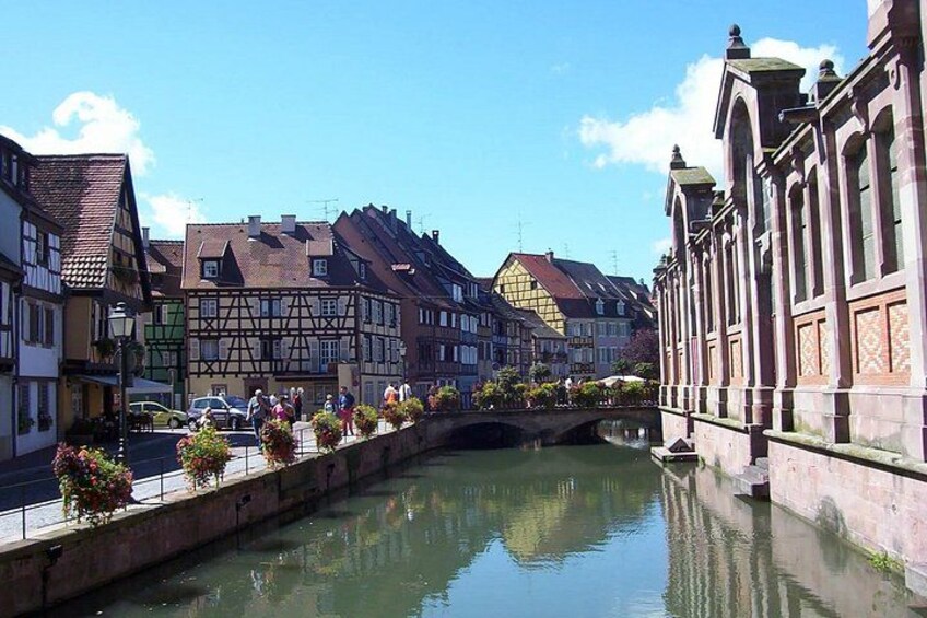 A canal with buildings on either side, a bridge, and a clear blue sky. 2