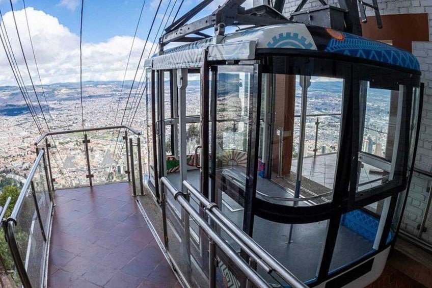 A cable car with a glass enclosure, a metal railing, and a cityscape in the background. 4