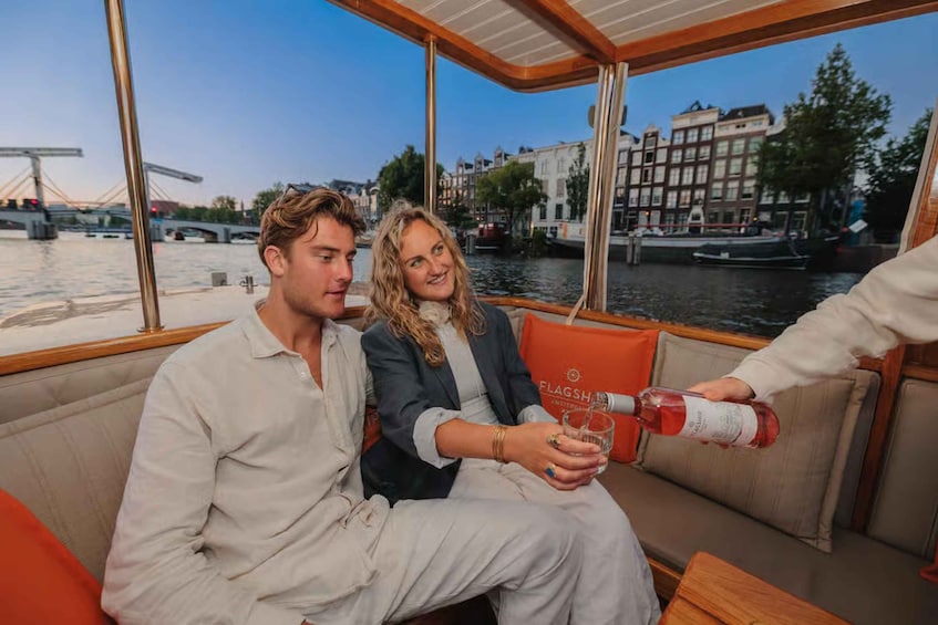 Two people on a boat with a cityscape and a bridge in the background. 5