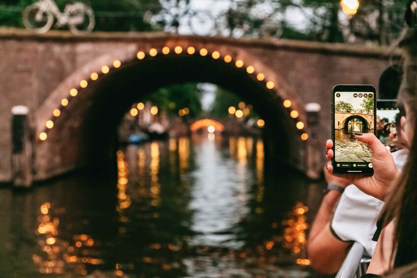 A person taking a photo of a bridge with lights and a canal. 4