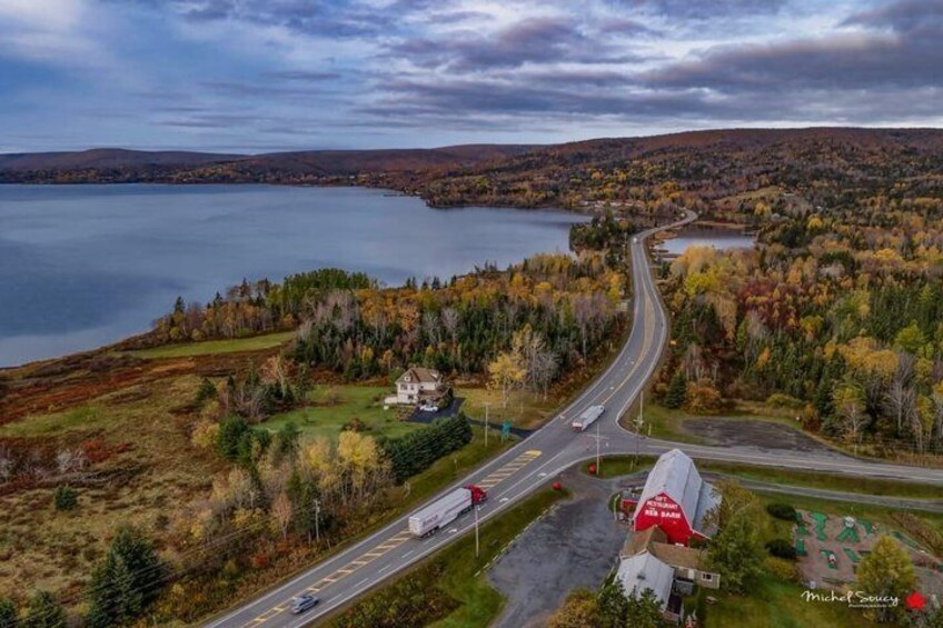 An aerial view of a road curving through a forested area with a lake in the background. 5
