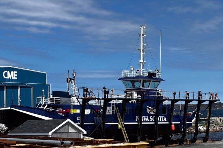 A ship docked at a port with a control tower, a blue building labeled 'CME,' and a sign reading 'NOVA SCOTIA.' 4