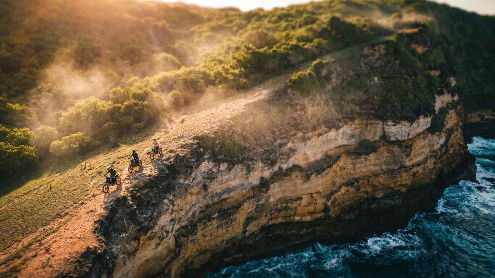 A group of mountain bikers on a rocky cliffside overlooking the ocean. 5