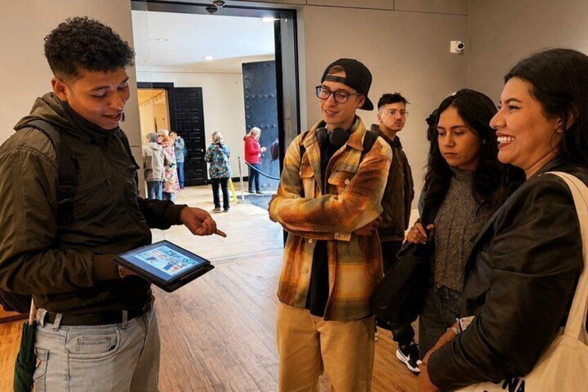 A group of people in a modern indoor setting, some holding a tablet. 4