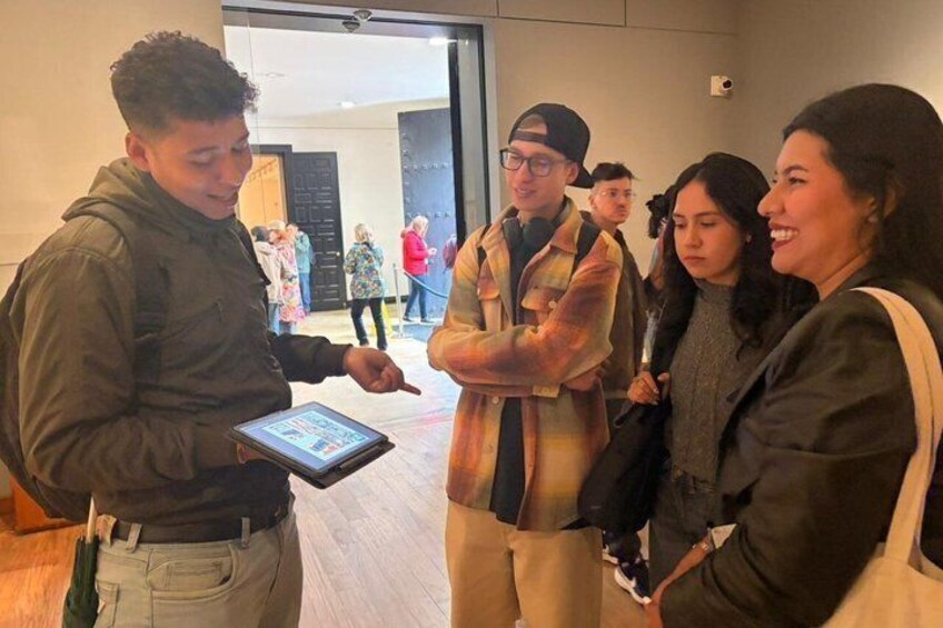 A group of people in an indoor setting, some holding a tablet. 3