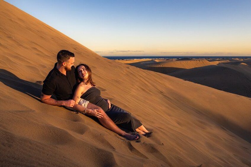 A couple lying on sand dunes during sunset. 1