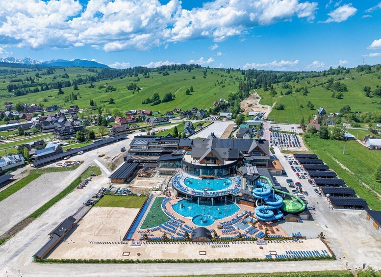 A resort with a large pool, water slides, and a mountainous backdrop. 4