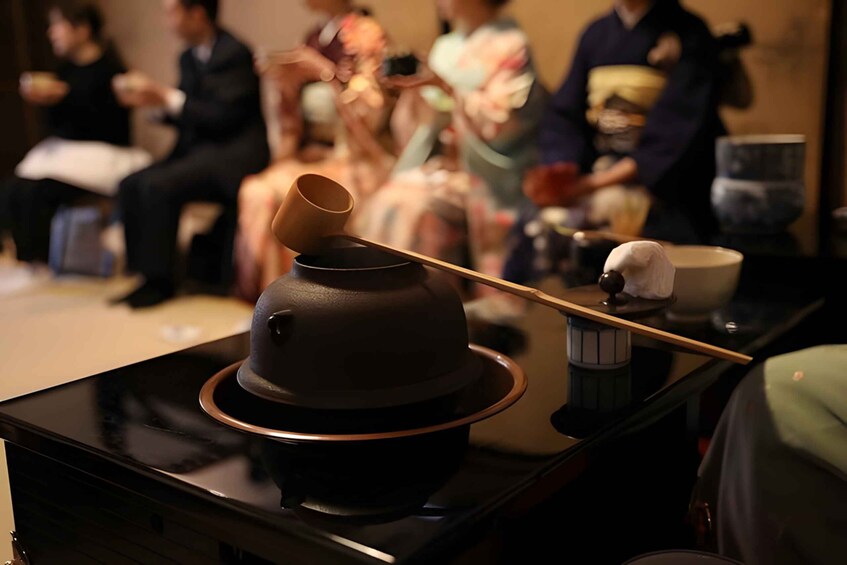 A traditional Japanese tea ceremony setup with a tea bowl, whisk, and a teapot on a tray. 1