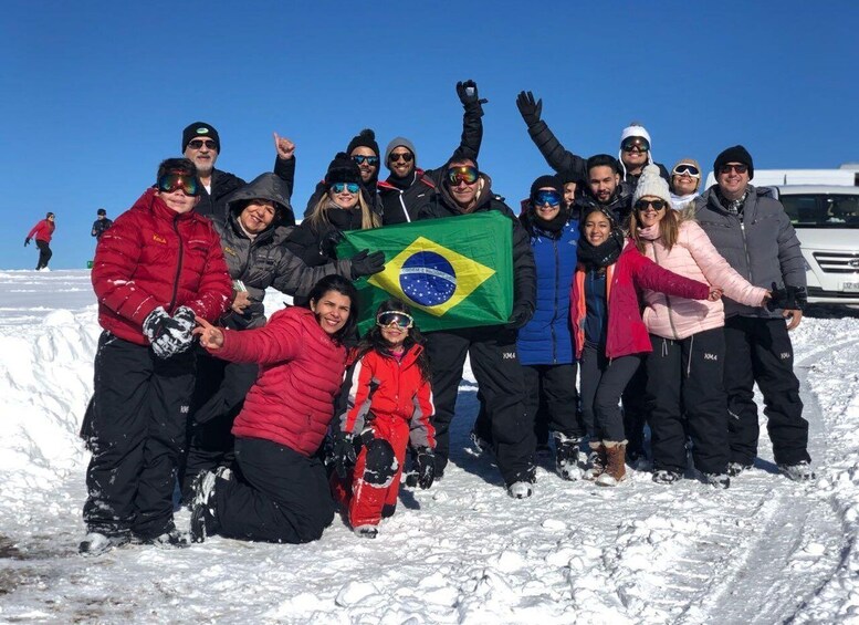 A group of people posing with a Brazilian flag in a snowy landscape. 3