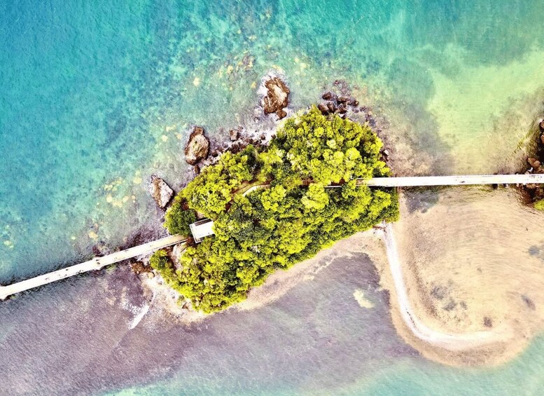 An aerial view of a tropical island with clear turquoise waters, a sandy beach, and dense green vegetation. 5