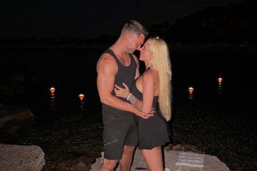 A couple embracing by a lake at night with lights reflecting on the water. 5