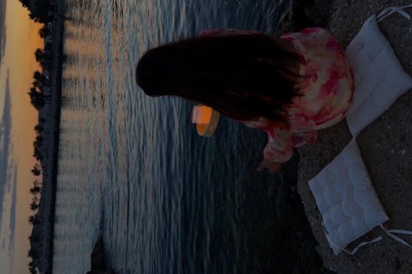 A person sitting by a body of water during sunset. 4