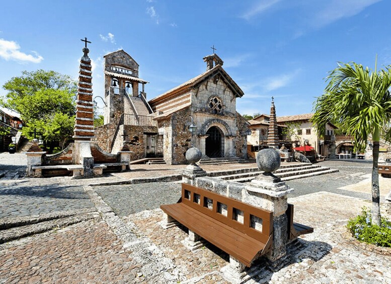 A historic church with a bell tower, a stone staircase, and a wooden bench in a cobblestone plaza. 5