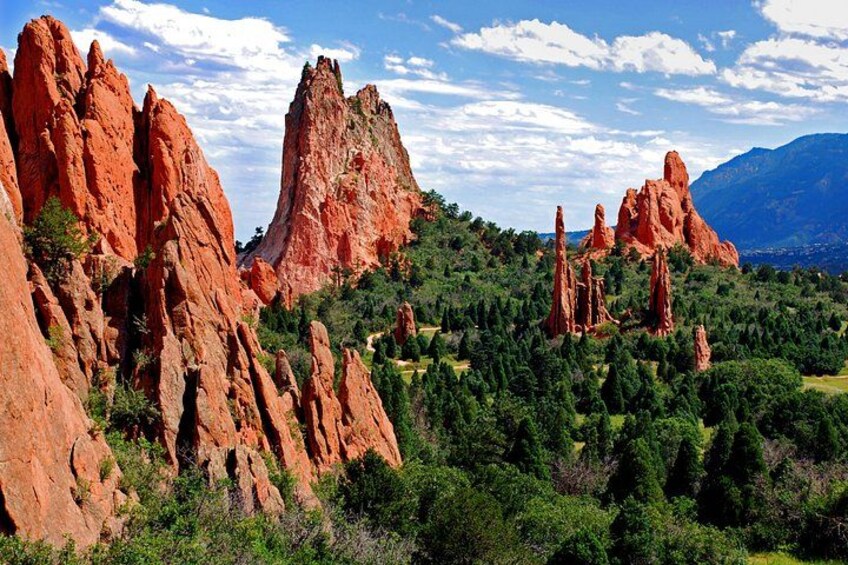 A landscape with red rock formations, green trees, and a mountain in the background. 4
