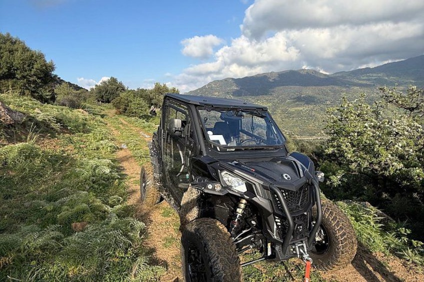 A black off-road vehicle on a dirt path with mountains in the background. 1