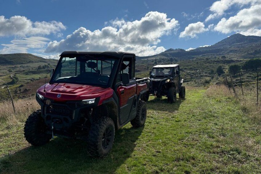 A red off-road vehicle and a black ATV on a grassy path with hills in the background. 2