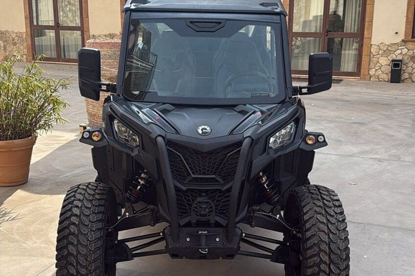 A black off-road vehicle parked in front of a building with a stone facade and large windows. 3