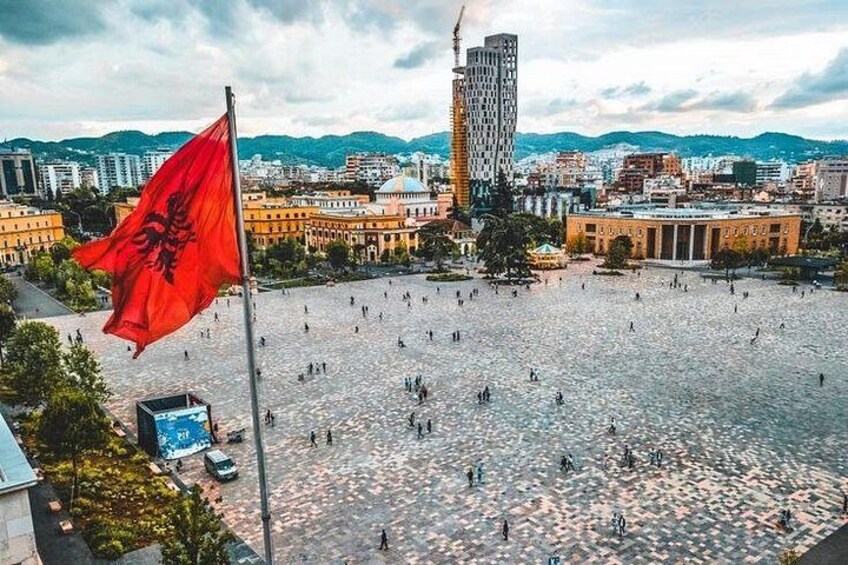 A city square with a flag, buildings, and a tall skyscraper. 4