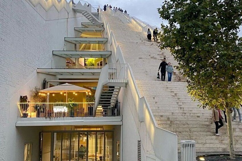 A multi-level building with a staircase, outdoor seating, and a tree. 3