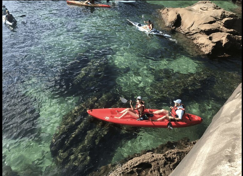 A group kayaking on clear water with rocky shores. 1