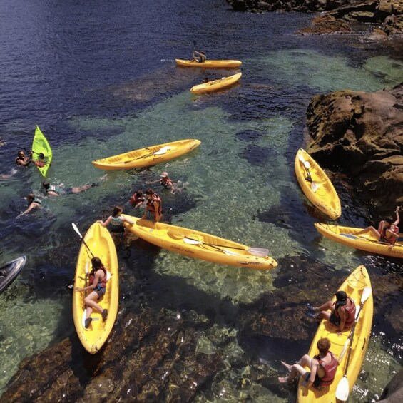 People kayaking in clear water near rocks. 2