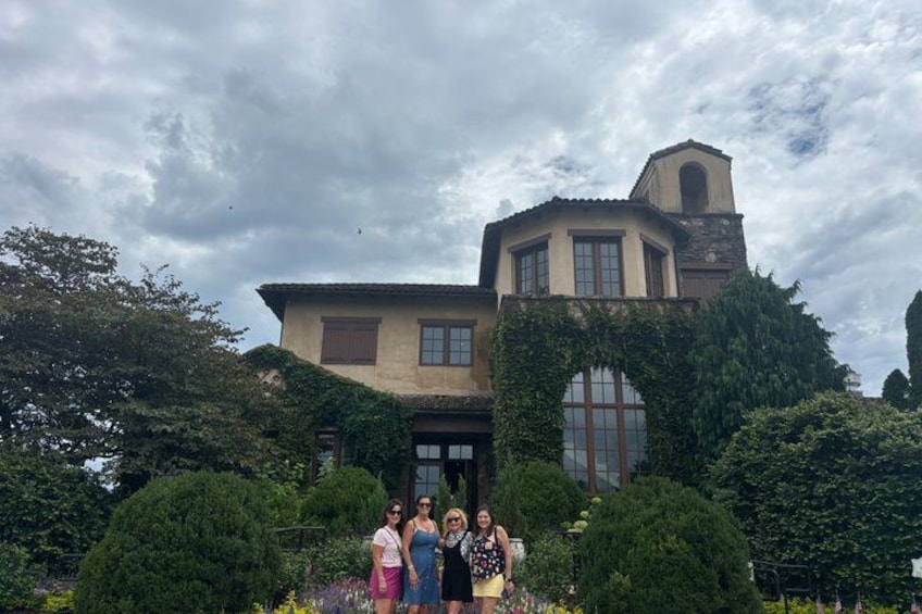 A large house with a bell tower, surrounded by lush greenery and a cloudy sky. 2