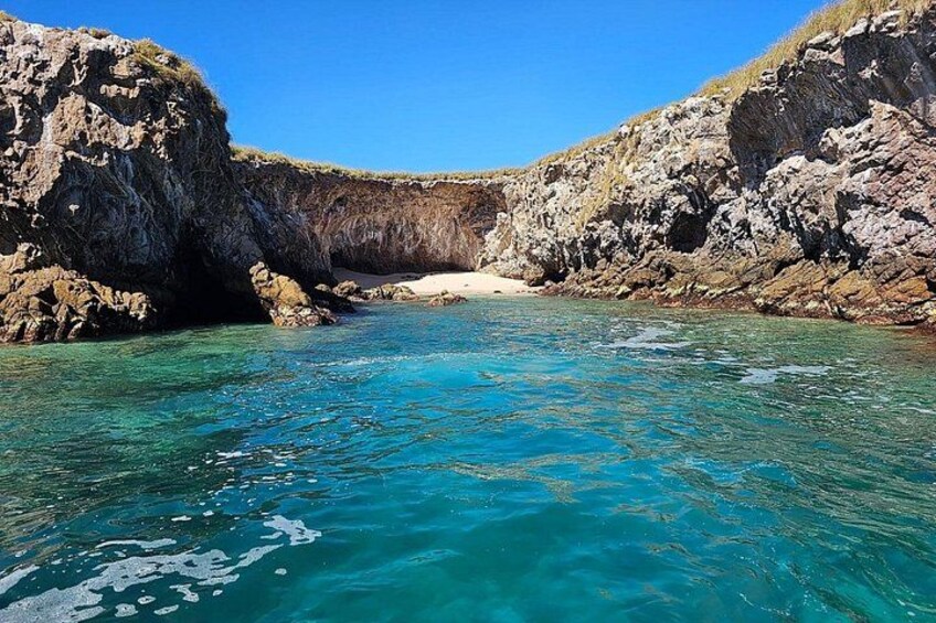 Un paisaje costero con aguas turquesas cristalinas, acantilados rocosos y una playa arenosa. 4